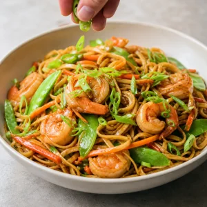 Zesty ginger shrimp lo mein with snow peas, carrots, and green onions.